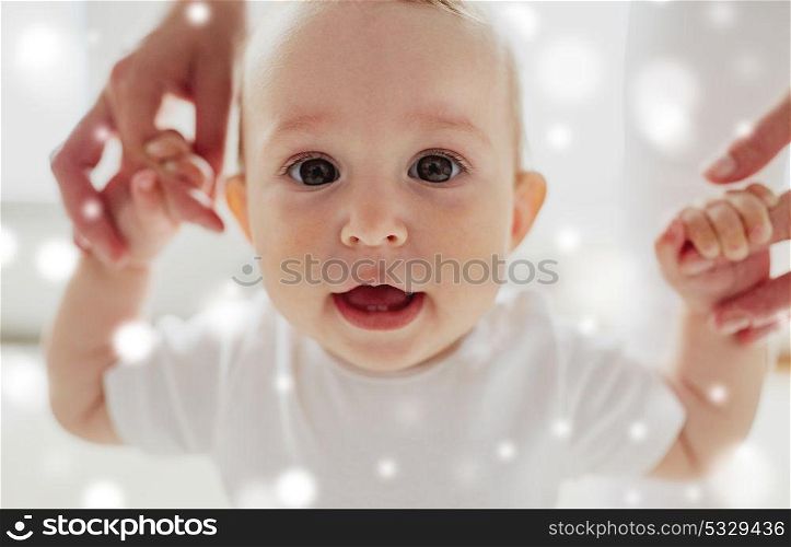 family, child, childhood and parenthood concept - portrait of happy little baby learning to walk with mother help over snow. happy baby learning to walk with mother help