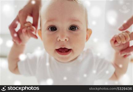 family, child, childhood and parenthood concept - portrait of happy little baby learning to walk with mother help over snow. happy baby learning to walk with mother help