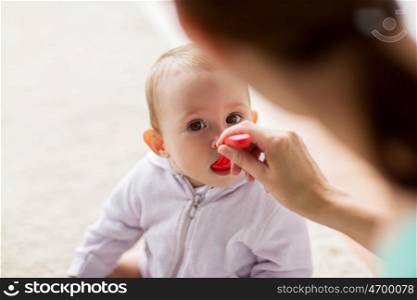 family, child, eating and parenthood concept - mother with spoon feeding little baby at home