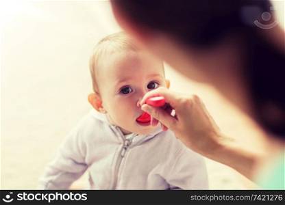 family, child, eating and parenthood concept - mother with spoon feeding little baby at home. mother with spoon feeding little baby at home