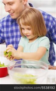 family, child, food and home concept - smiling father and little girl at kitchen cooking salad