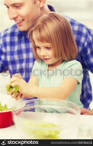 family, child, food and home concept - smiling father and little girl at kitchen cooking salad