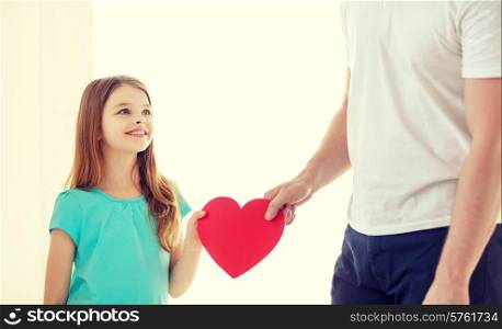 family child, health, charity and love concept - smiling little girl and father holding red heart