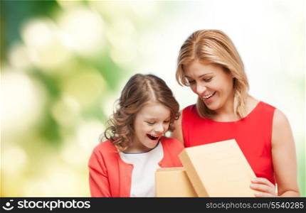 family, child, holiday and party concept - smiling mother and daughter opening gift box
