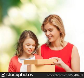 family, child, holiday and party concept - smiling mother and daughter opening gift box