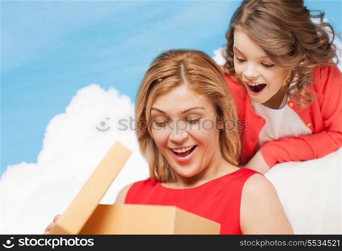 family, child, holiday and party concept - smiling mother and daughter with gift box