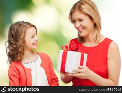 family, child, holiday and party concept - smiling mother and daughter with gift box