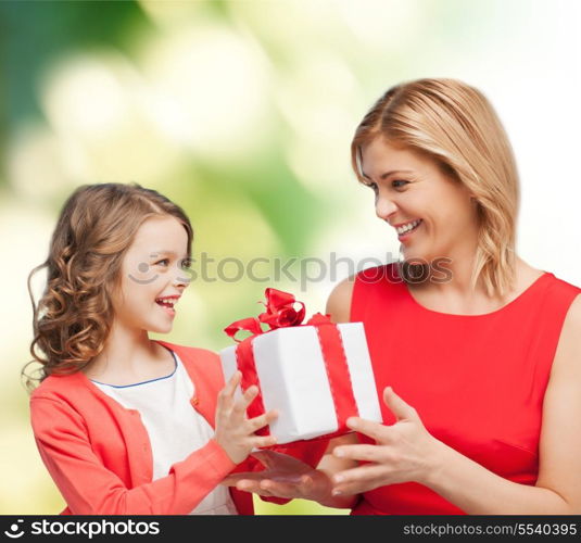 family, child, holiday and party concept - smiling mother and daughter with gift box