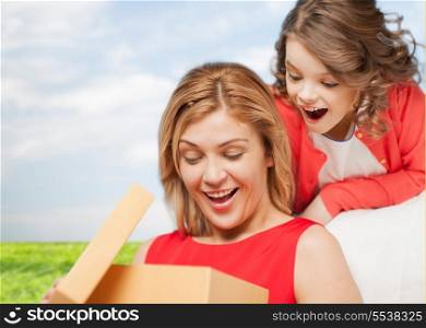 family, child, holiday and party concpt - smiling mother and daughter with gift box