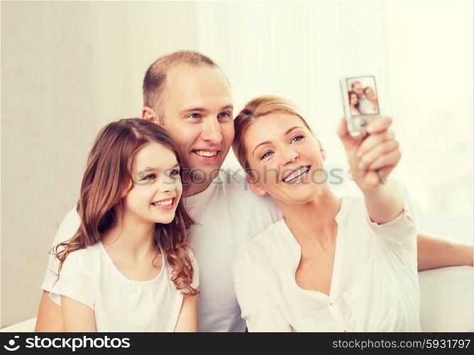 family, child, photography and home concept - happy family with little girl making self portrait with digital camera