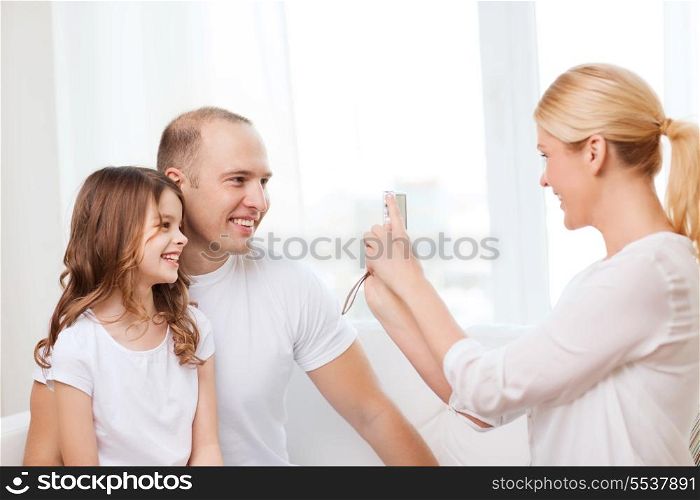 family, child, photography and home concept - smiling happy mother taking picture of father and daughter