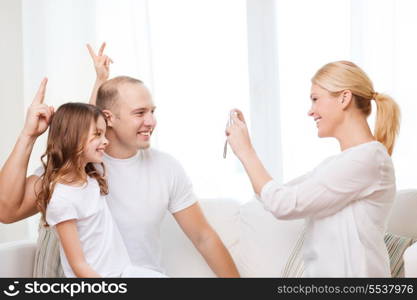 family, child, photography and home concept - smiling happy mother taking picture of father and daughter