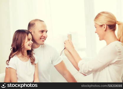 family, child, photography and home concept - smiling happy mother taking picture of father and daughter