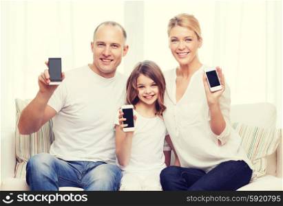 family, child, technology and home concept - smiling parents and little girl with blank black screen smartphones at home
