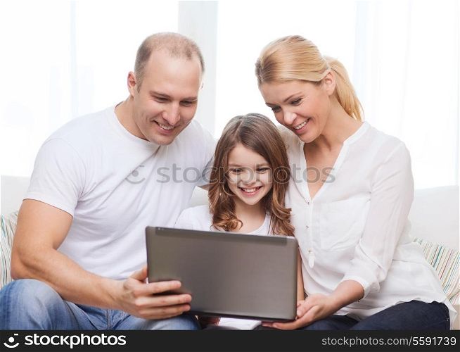 family, child, technology and home concept - smiling parents and little girl with laptop at home