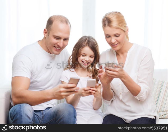 family, child, technology and home concept - smiling parents and little girl with smartphones at home