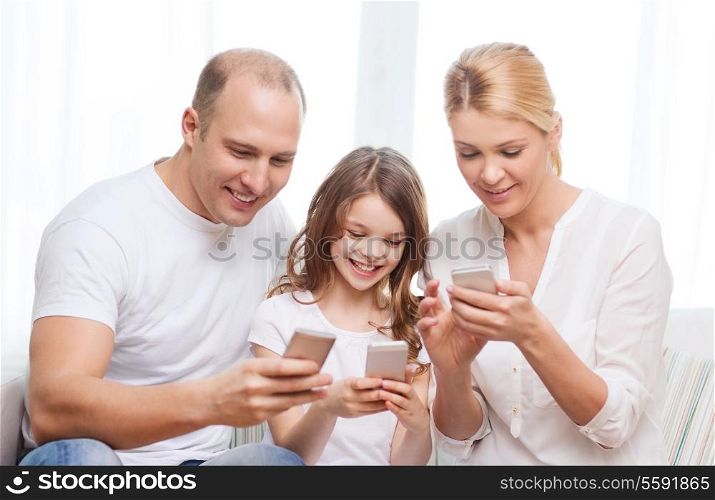 family, child, technology and home concept - smiling parents and little girl with smartphones at home