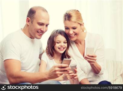 family, child, technology and home concept - smiling parents and little girl with smartphones at home