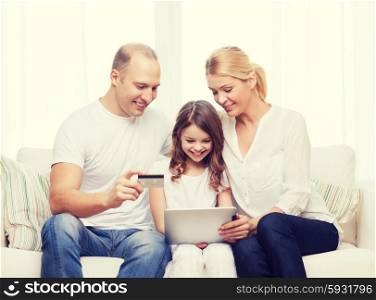 family, child, technology, money and home concept - smiling parents and little girl with tablet pc and credit card at home