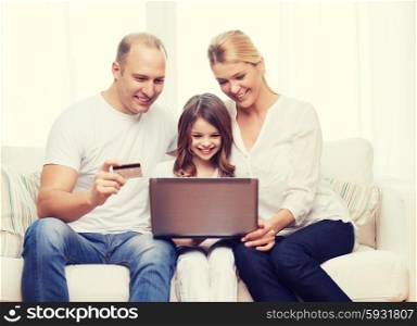 family, child, technology, money and home concept - smiling parents and little girl with laptop and credit card at home