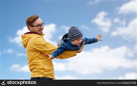 family, childhood and fatherhood concept - happy father and little son playing and having fun outdoors over blue sky and clouds background. father with son playing and having fun outdoors