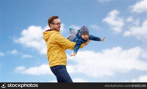 family, childhood and fatherhood concept - happy father and little son playing and having fun outdoors over blue sky and clouds background. father with son playing and having fun outdoors. father with son playing and having fun outdoors