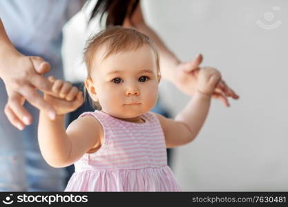 family, childhood and motherhood concept - little baby girl learning to walk with mother&rsquo;s help at home. baby girl learning to walk with mother&rsquo;s help