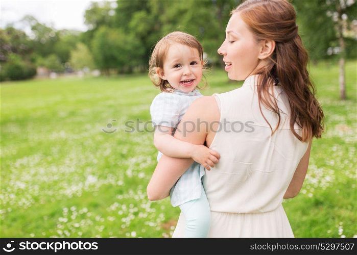 family, childhood and parenthood concept - happy mother holding little baby girl at summer park. happy mother holding baby girl at summer park