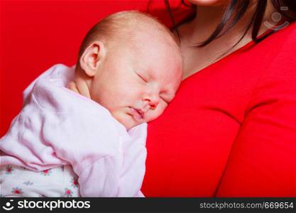 Family, childhood and parenthood concept. Little newborn baby sleeping on mother chest. Red background. Little newborn baby sleeping on mother chest