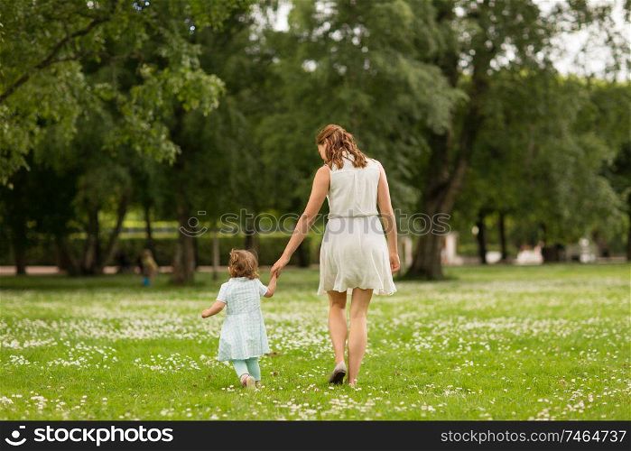 family, childhood and parenthood concept - mother with little baby daughter walking at summer park. mother with baby daughter walking at summer park