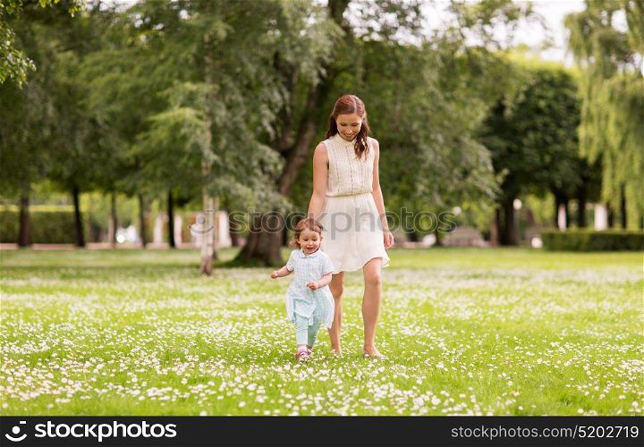 family, childhood and parenthood concept - mother with little baby girl walking at summer park. mother with baby girl walking at summer park
