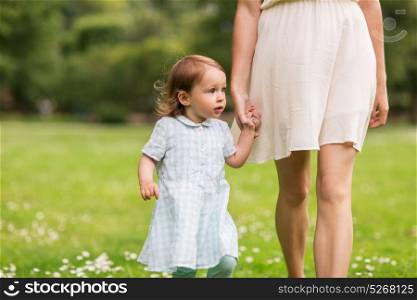 family, childhood and parenthood concept - mother with little baby girl walking at summer park. mother with baby girl walking at summer park