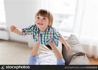 family, childhood and people concept - father hands holding happy little boy at home. father hands holding happy little boy at home