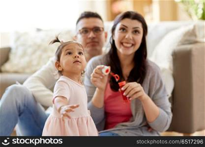 family, childhood and people concept - happy mother blowing soap bubbles and playing with little daughter at home. family with soap bubbles playing at home. family with soap bubbles playing at home