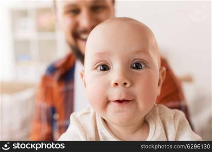 family, childhood, babyhood and people concept - close up of happy little baby boy with father at home. close up of happy little baby boy with father
