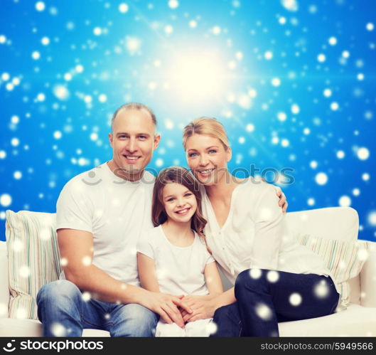 family, childhood, christmas holidays and people concept - smiling mother, father and little girl over blue snowy background