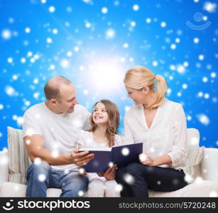 family, childhood, christmas holidays and people - smiling mother, father and little girl reading book over blue snowy background