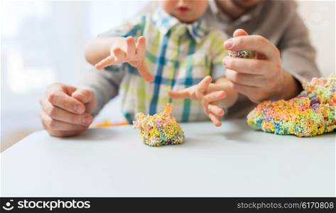 family, childhood, creativity, activity and people concept - close up of happy father and little son playing with ball clay at home