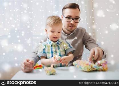 family, childhood, creativity, activity and people concept - happy father and little son playing with ball clay at home over snow