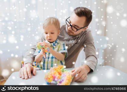 family, childhood, creativity, activity and people concept - happy father and little son playing with ball clay at home over snow