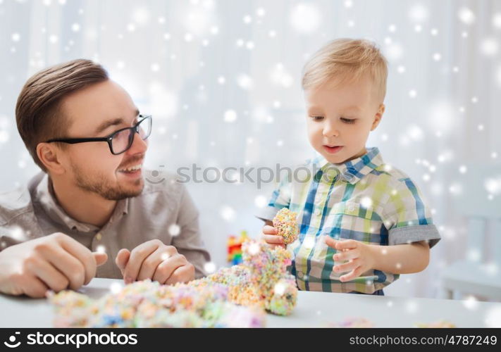 family, childhood, creativity, activity and people concept - happy father and little son playing with ball clay at home over snow