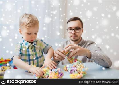 family, childhood, creativity, activity and people concept - happy father and little son playing with ball clay at home over snow. father and son playing with ball clay at home