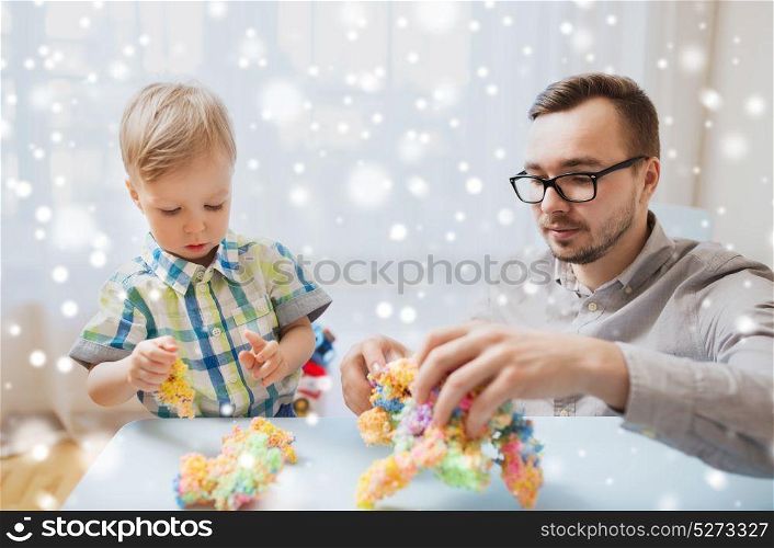 family, childhood, creativity, activity and people concept - happy father and little son playing with ball clay at home over snow. father and son playing with ball clay at home