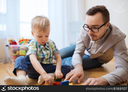 family, childhood, creativity, activity and people concept - happy father and little son playing with toy blocks at home