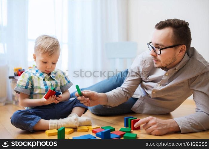 family, childhood, creativity, activity and people concept - happy father and little son playing with toy blocks at home