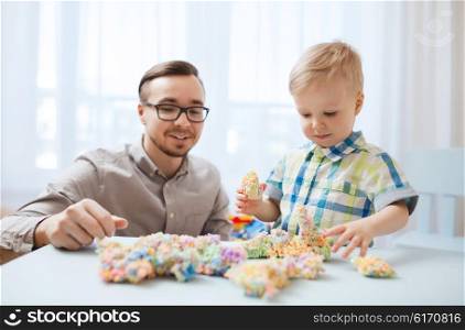 family, childhood, creativity, activity and people concept - happy father and little son playing with ball clay at home