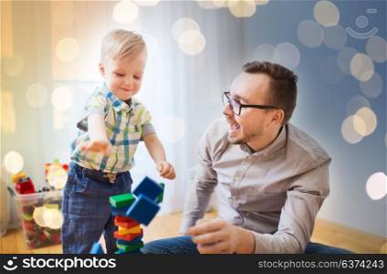 family, childhood, creativity, activity and people concept - happy father and little son playing with toy blocks at home. father and son playing with toy blocks at home