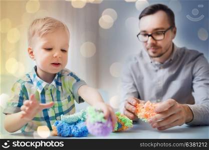 family, childhood, creativity, activity and people concept - happy father and little son playing with ball clay at home. father and son playing with ball clay at home