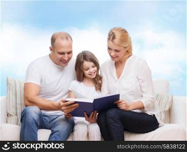 family, childhood, dream and people - smiling mother, father and little girl reading book over blue sky background