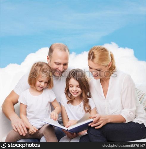 family, childhood, dream and people - smiling mother, father and little girls reading book over blue sky and cloud background